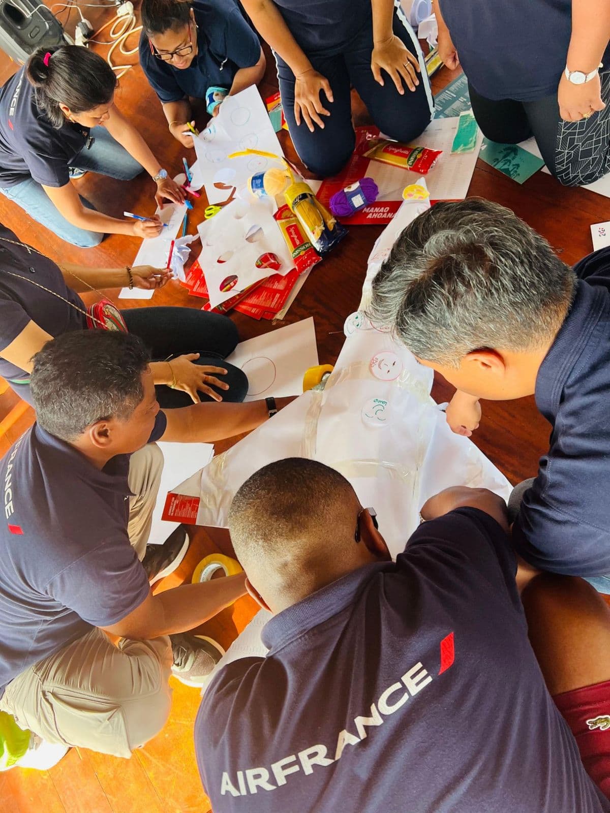 Participants à genoux autour d'un grand papier blanc pendant un atelier créatif en équipe